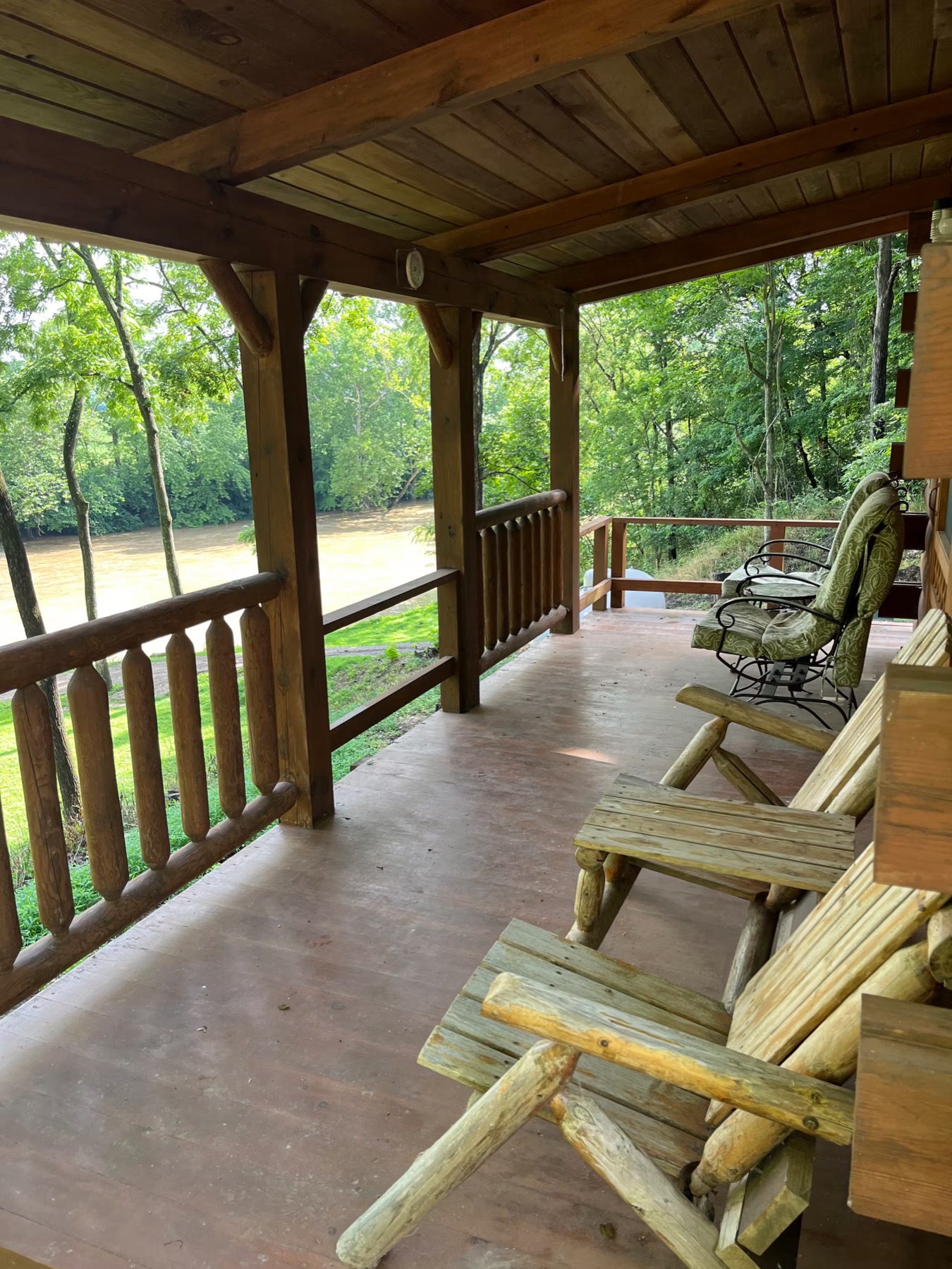 Covered porch of Cozy Creekside Cabin looking out over the creek and woods